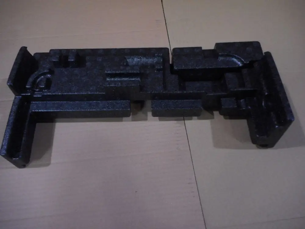 Schwarzer Kunststoffblock mit spezifischen Aussparungen, vermutlich für einen hydraulischen Deckel. Produkt von Remeha, auf einer braunen Pappe liegend.